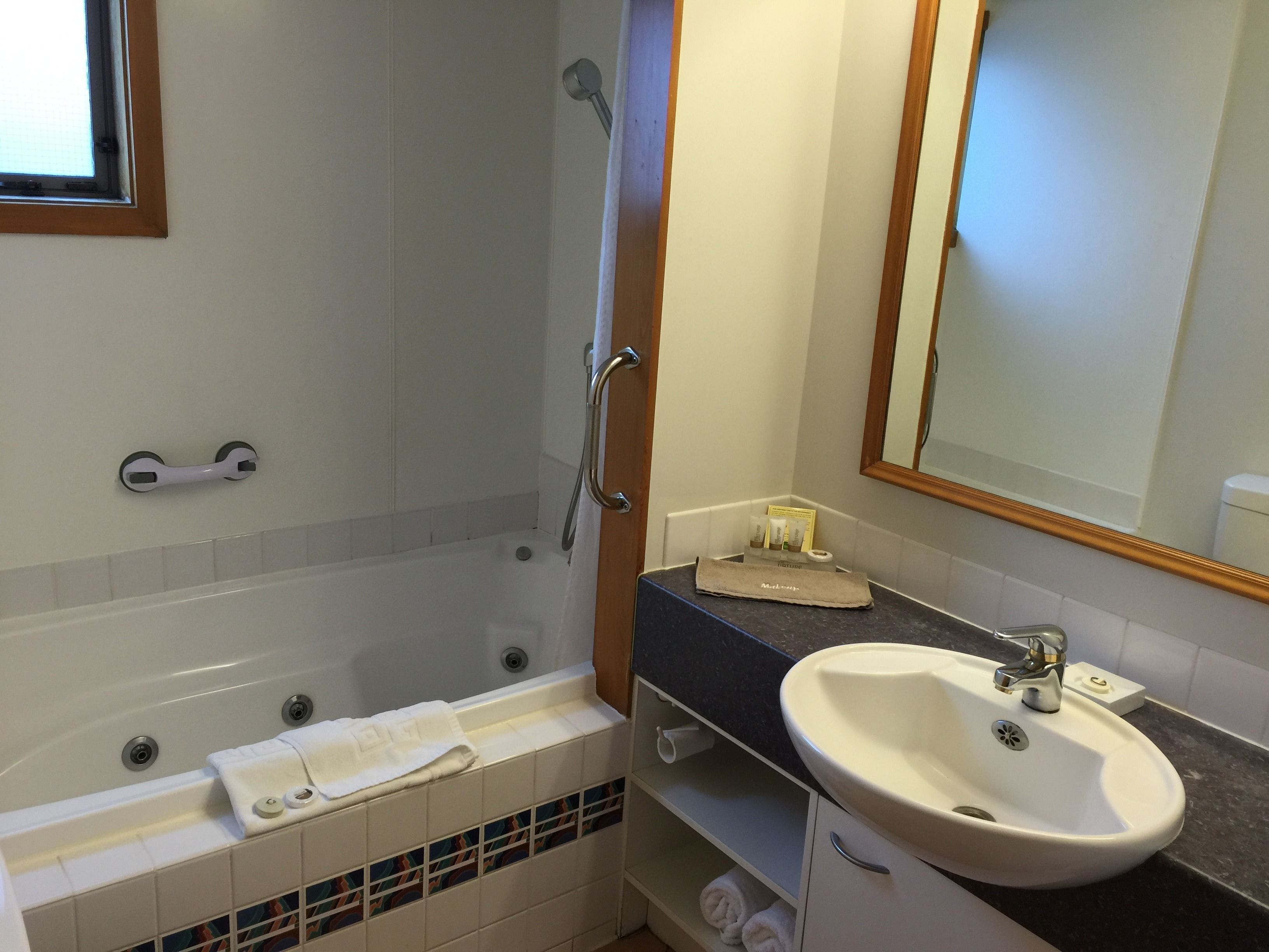 A bathroom with a bathtub, a sink, and a mirror.