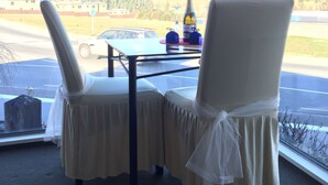 Una stanza con due sedie, un tavolo, una bottiglia e una borsa su un davanzale.