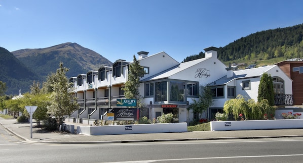 Un hôtel doté d’une réception, d’une enseigne « Quality Inn » et ayant une chaîne de montagnes en arrière-plan.