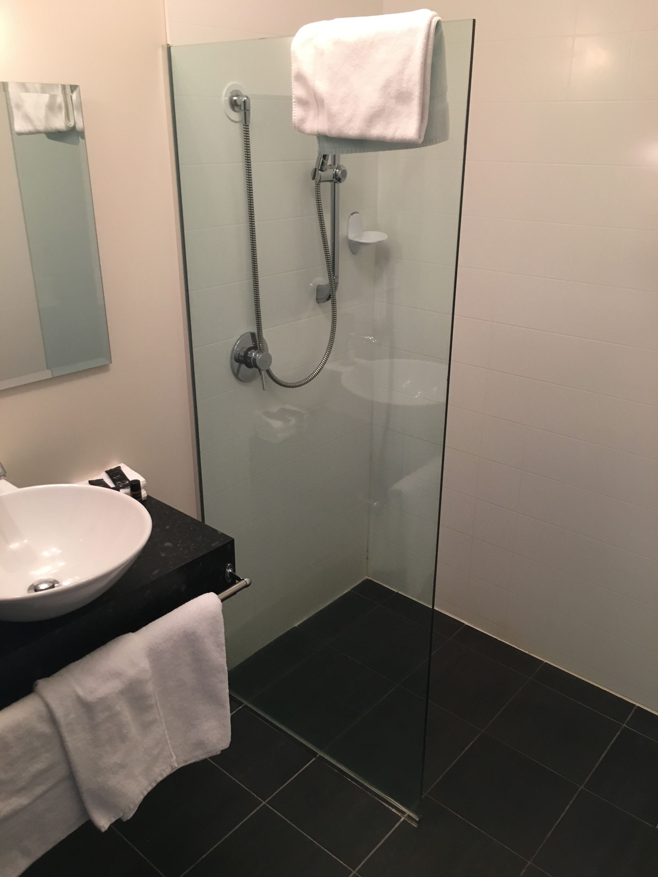 A modern bathroom with a glass-enclosed shower, a white sink, and a black countertop.