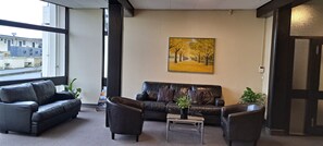 Un lobby moderno con sofás de cuero, una mesa de centro y un ventanal con vistas al exterior.