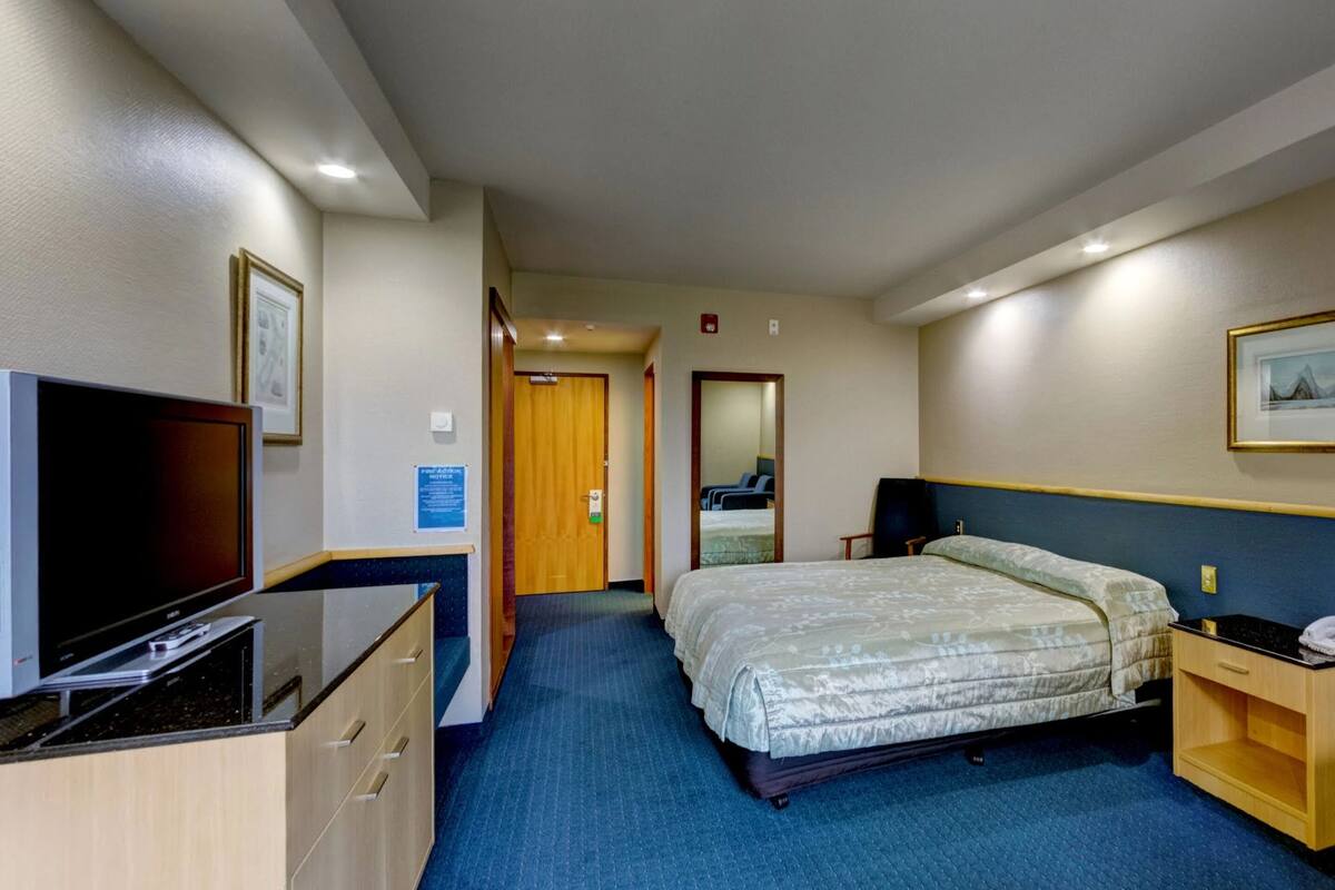 A hotel room with a bed, a TV, a desk, and a chair.