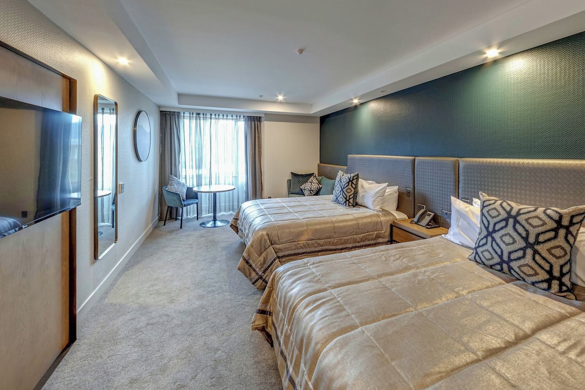A hotel room with two beds, a TV, a desk, and a chair.