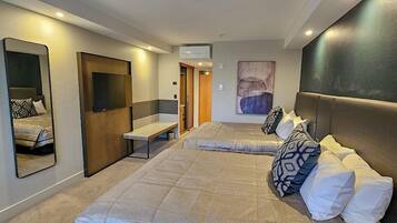 A hotel room with two beds, a large mirror, a bench, and a painting on the wall.