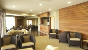 A spacious lobby with wicker furniture, a reception desk, and a wooden wall. - Distinction Luxmore Hotel (Te Anau)