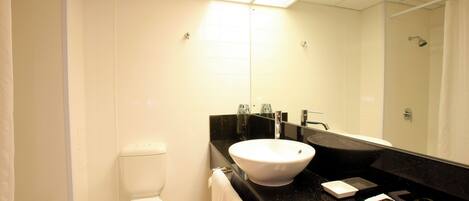 A modern bathroom with a white toilet, a black countertop sink, and a large mirror.