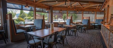 A restaurant with wooden beams, large windows, and a carpeted floor.