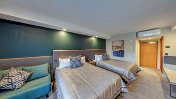 A hotel room with two beds, a sofa, and a wooden door.