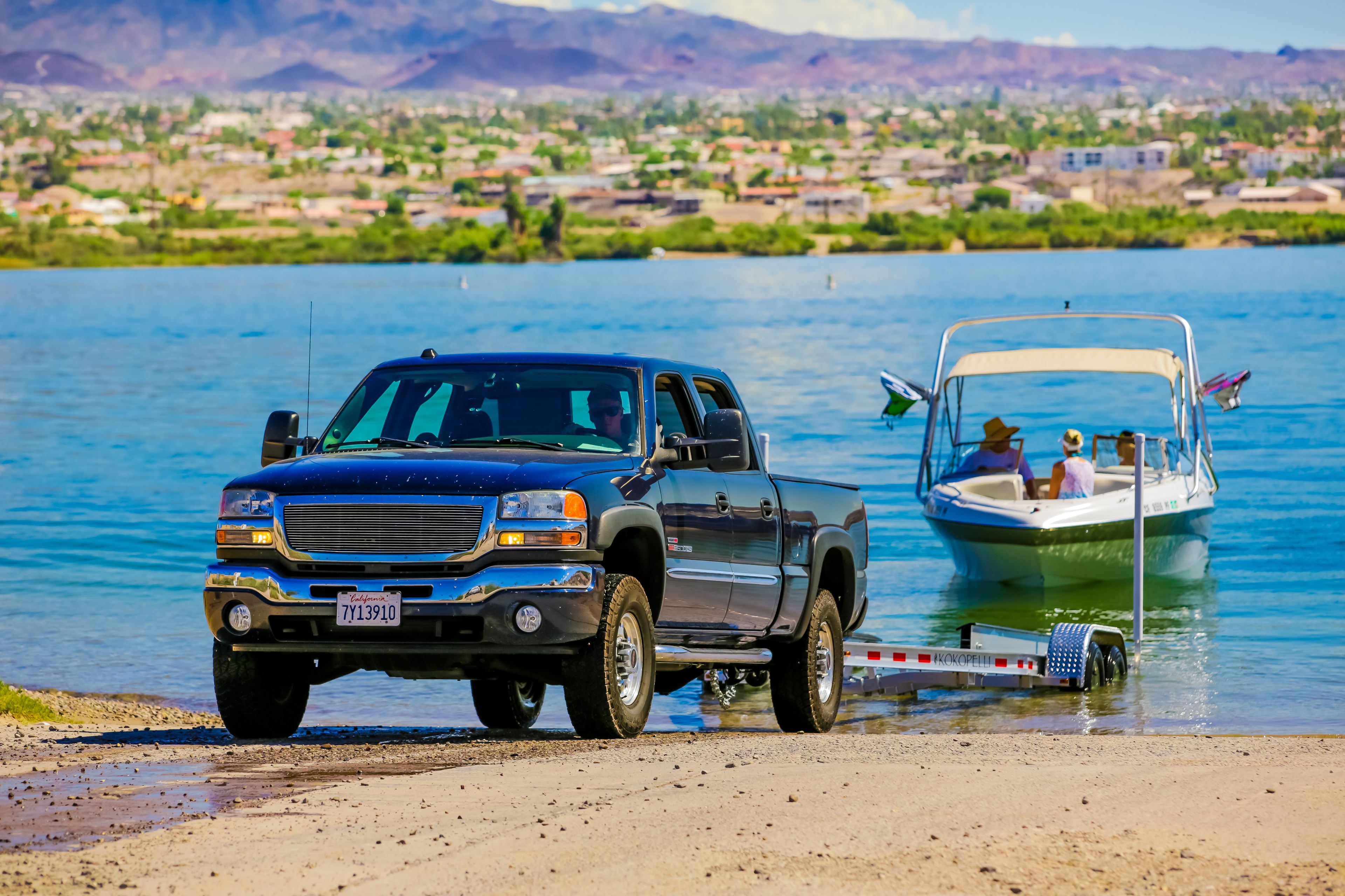 Un camionnette est garée au bord d’un lac, et un bateau est attaché à sa remorque.