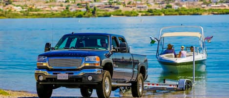 Un camionnette est garée au bord d’un lac, et un bateau est attaché à sa remorque.