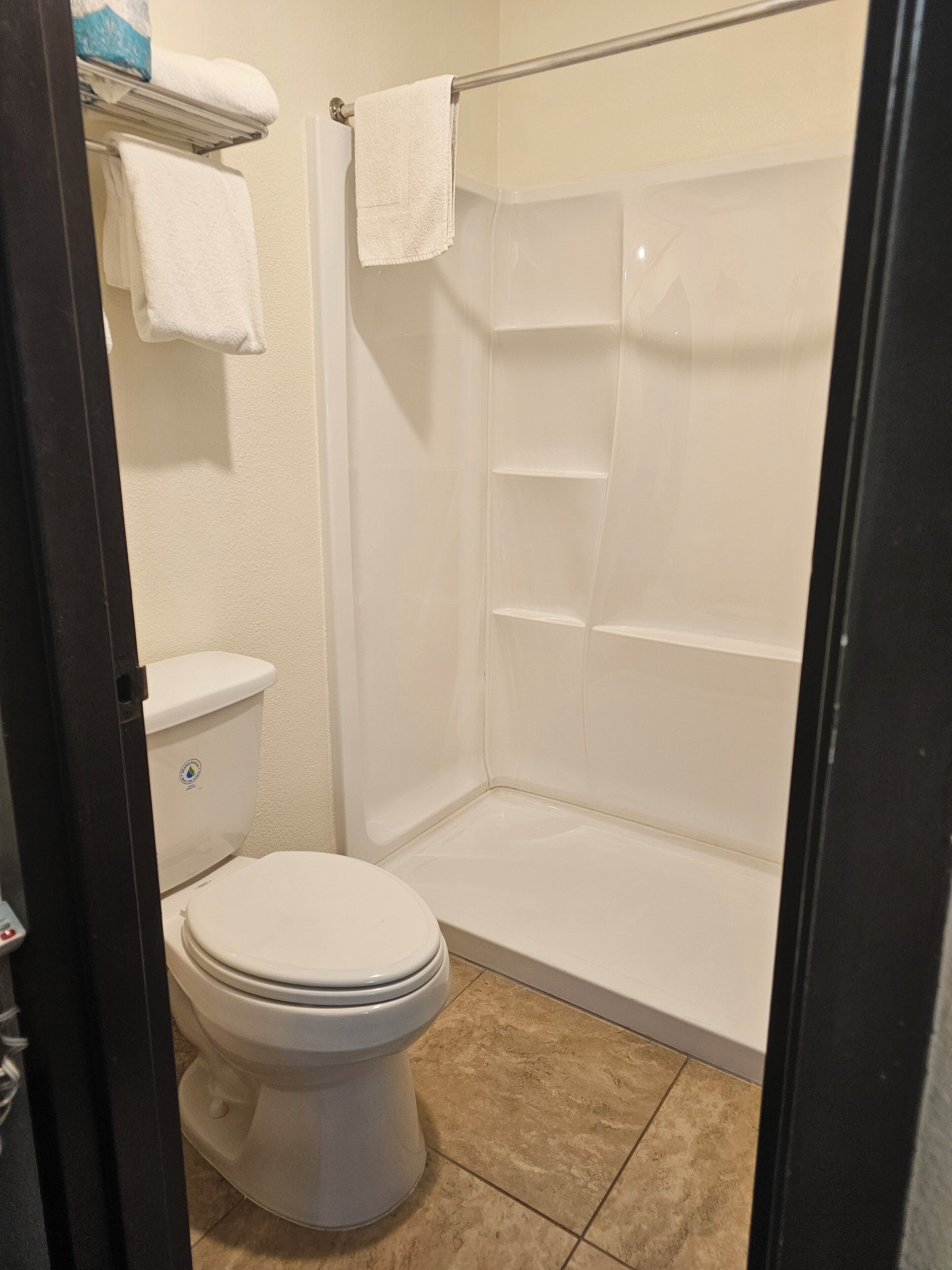 A bathroom with a toilet, a shower stall, and a towel rack.