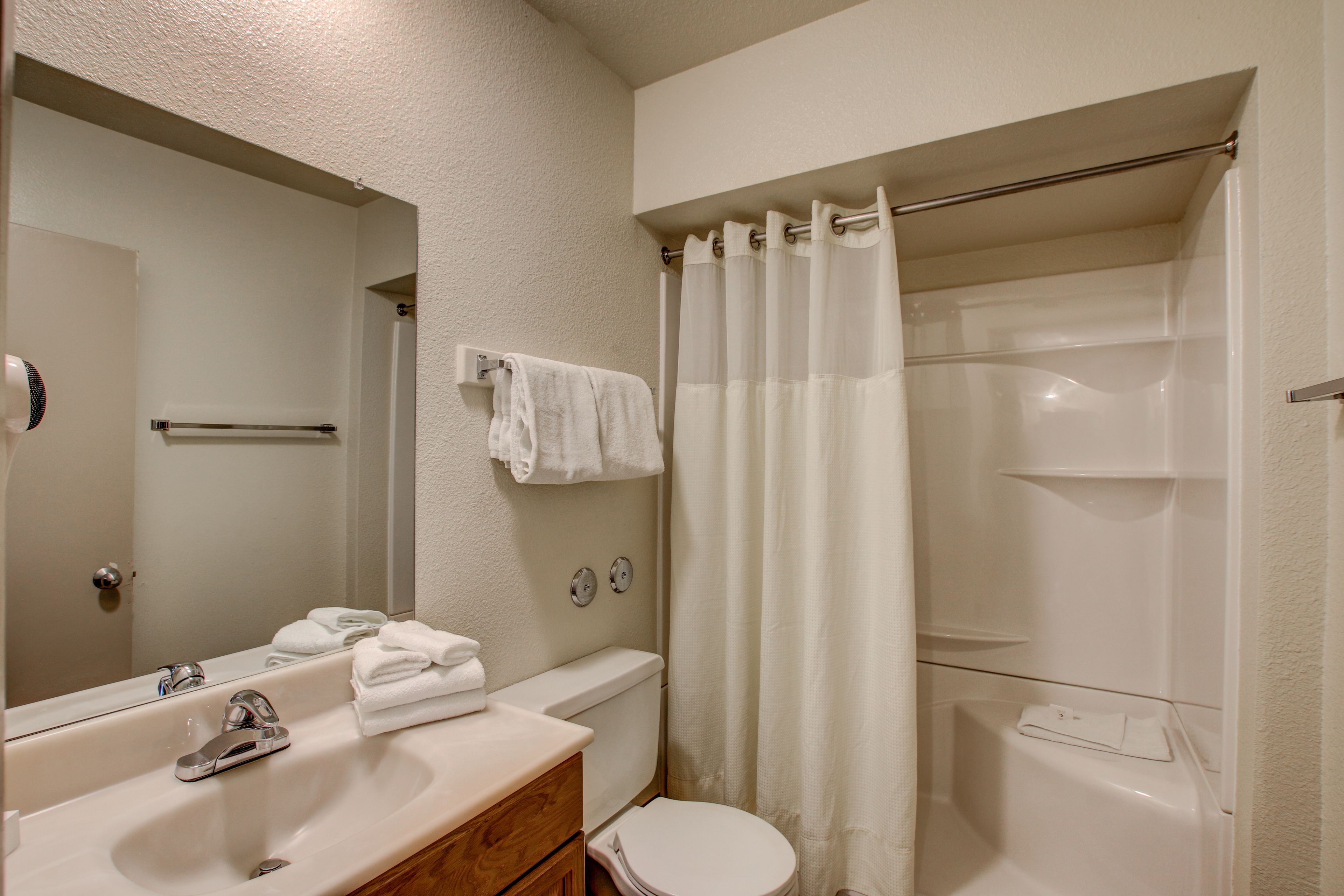 Baño con lavabo, espejo, inodoro y cortina de ducha.