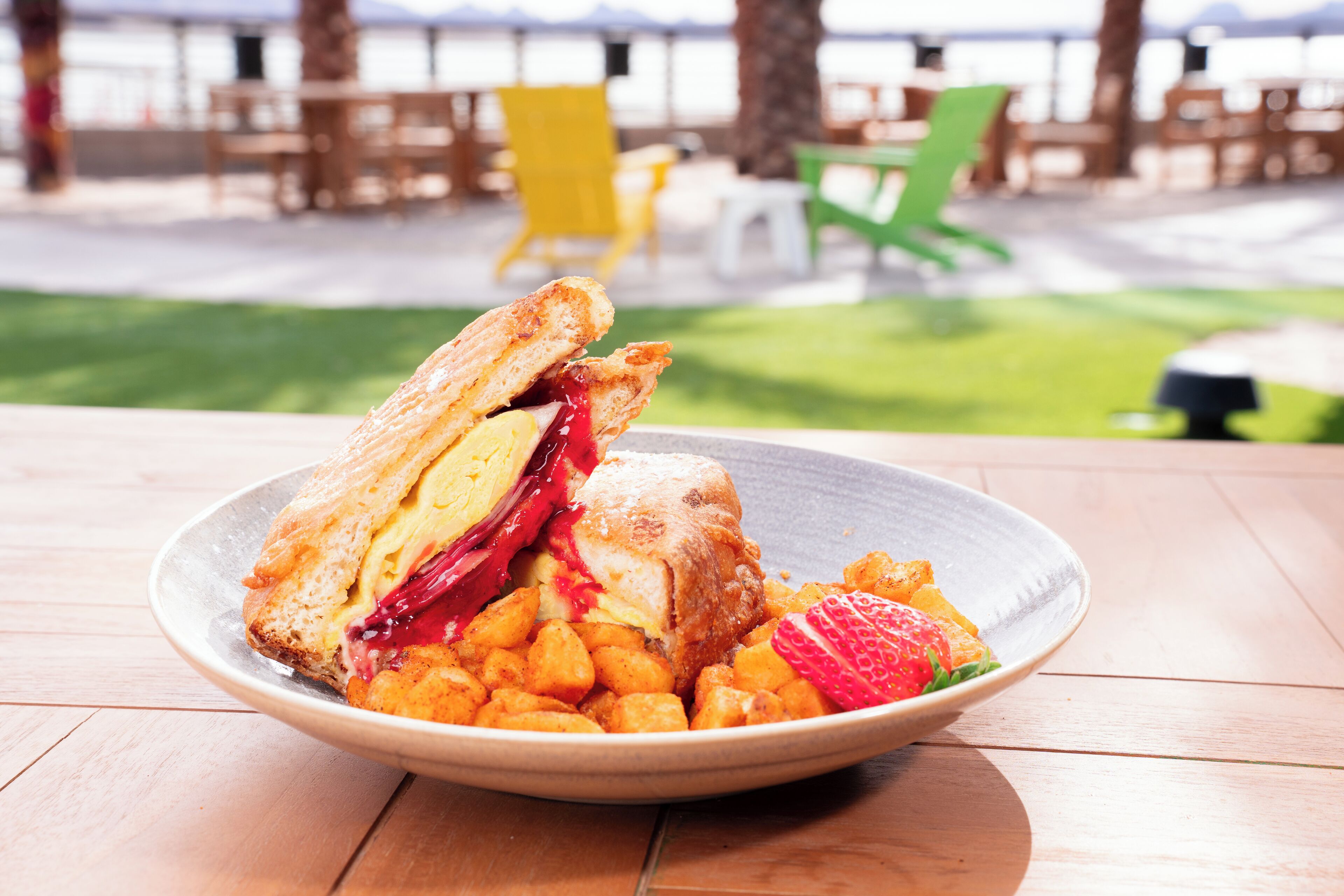 A plate with a sandwich and fruit on a wooden table.