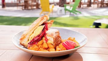 A plate with a sandwich and fruit on a wooden table.