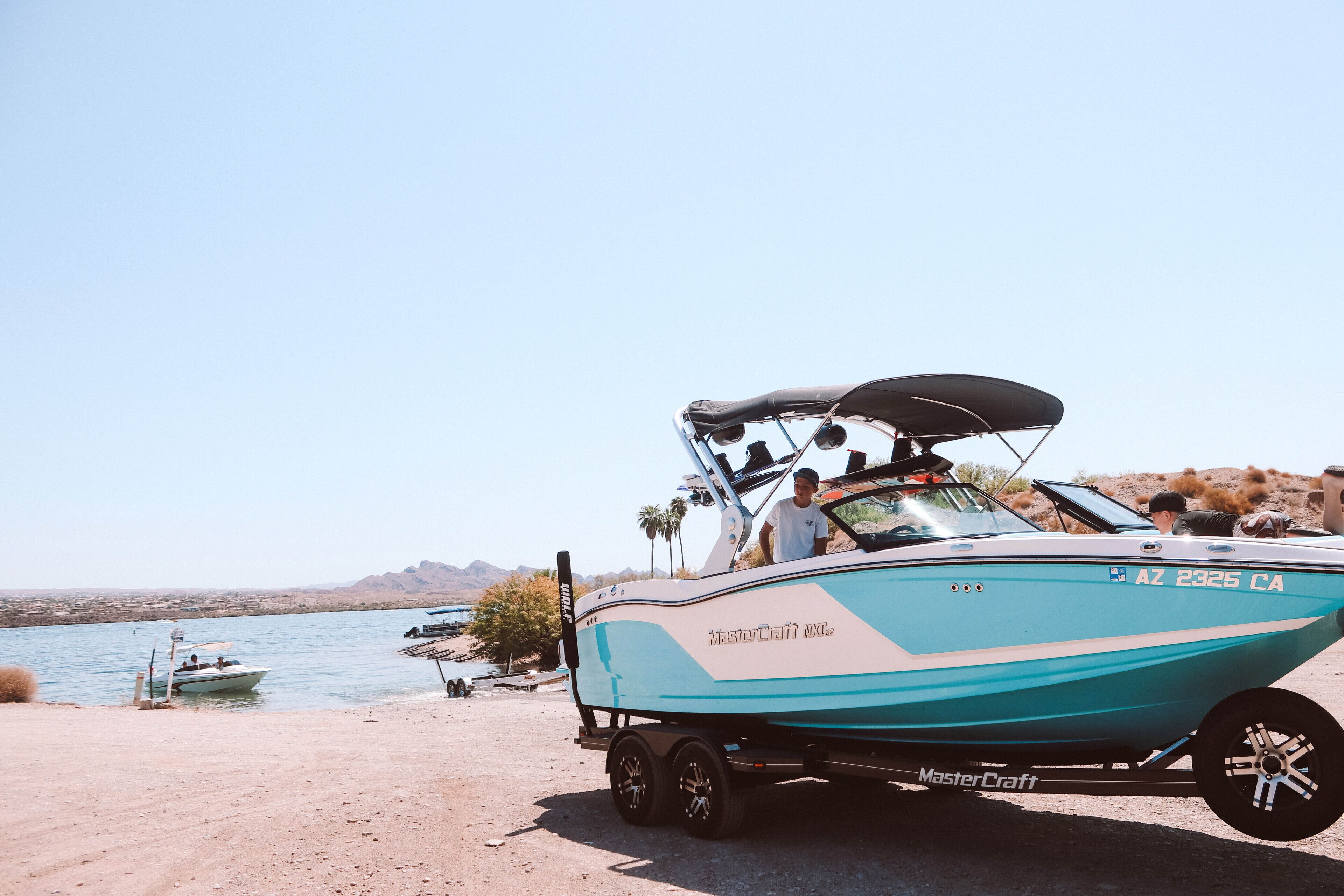 A boat with a trailer parked by a lake.