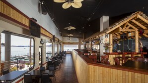 Een restaurant met een lange toonbank, meerdere plafondventilatoren en uitzicht op zee.
