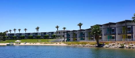 Un hotel moderno con varios pisos, ubicación frente al mar y palmeras.