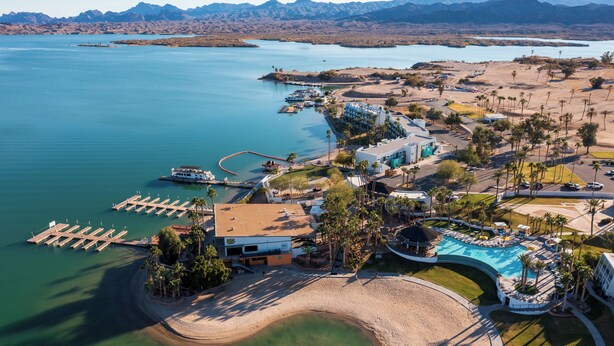 Een luchtbeeld van een resort met een jachthaven, zwembad en strand.