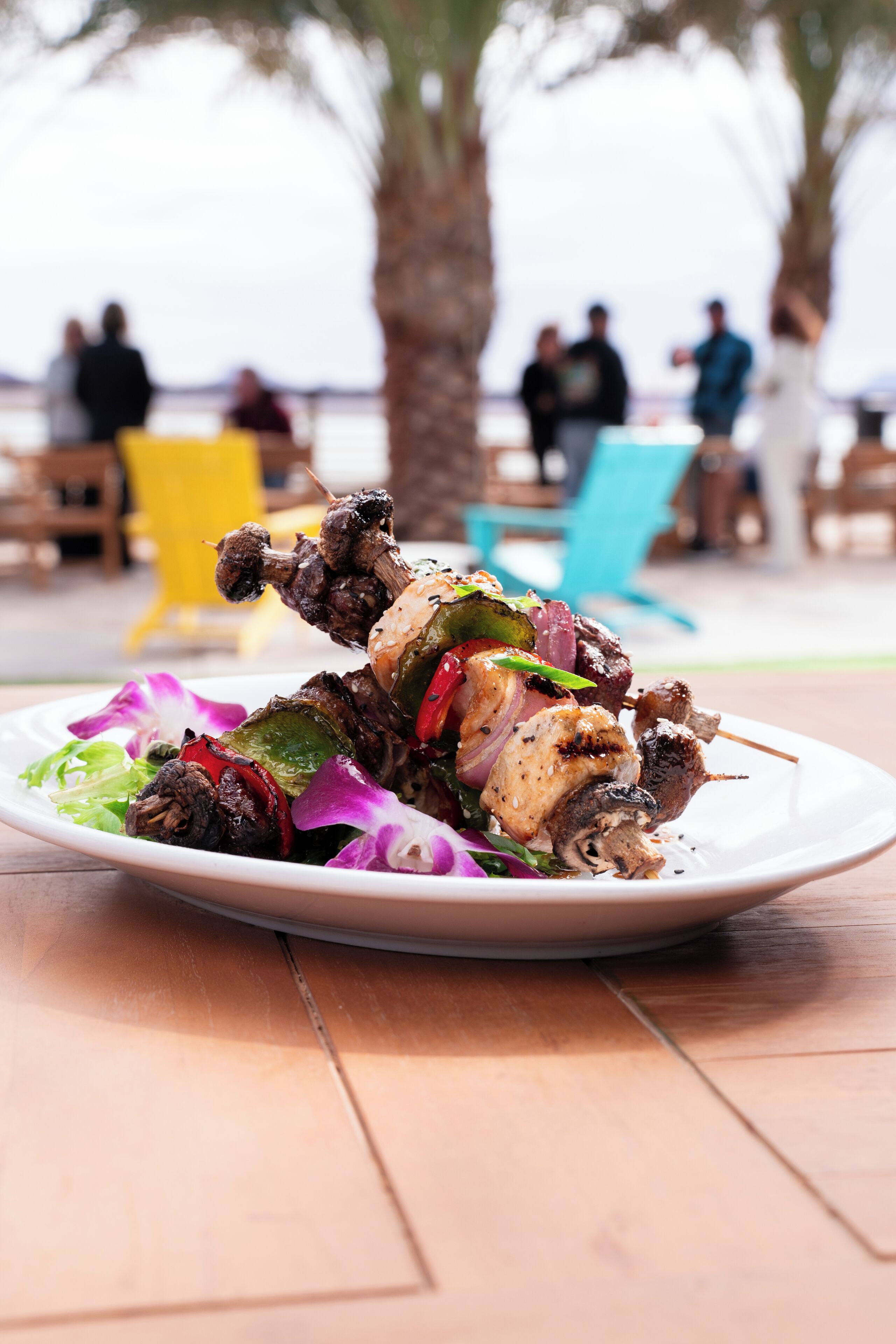 A plate of skewered meat and vegetables on a wooden table.