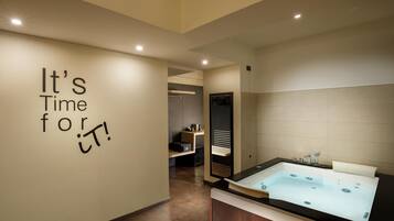 A modern bathroom with a large bathtub, a mirror, and a wall with motivational text.