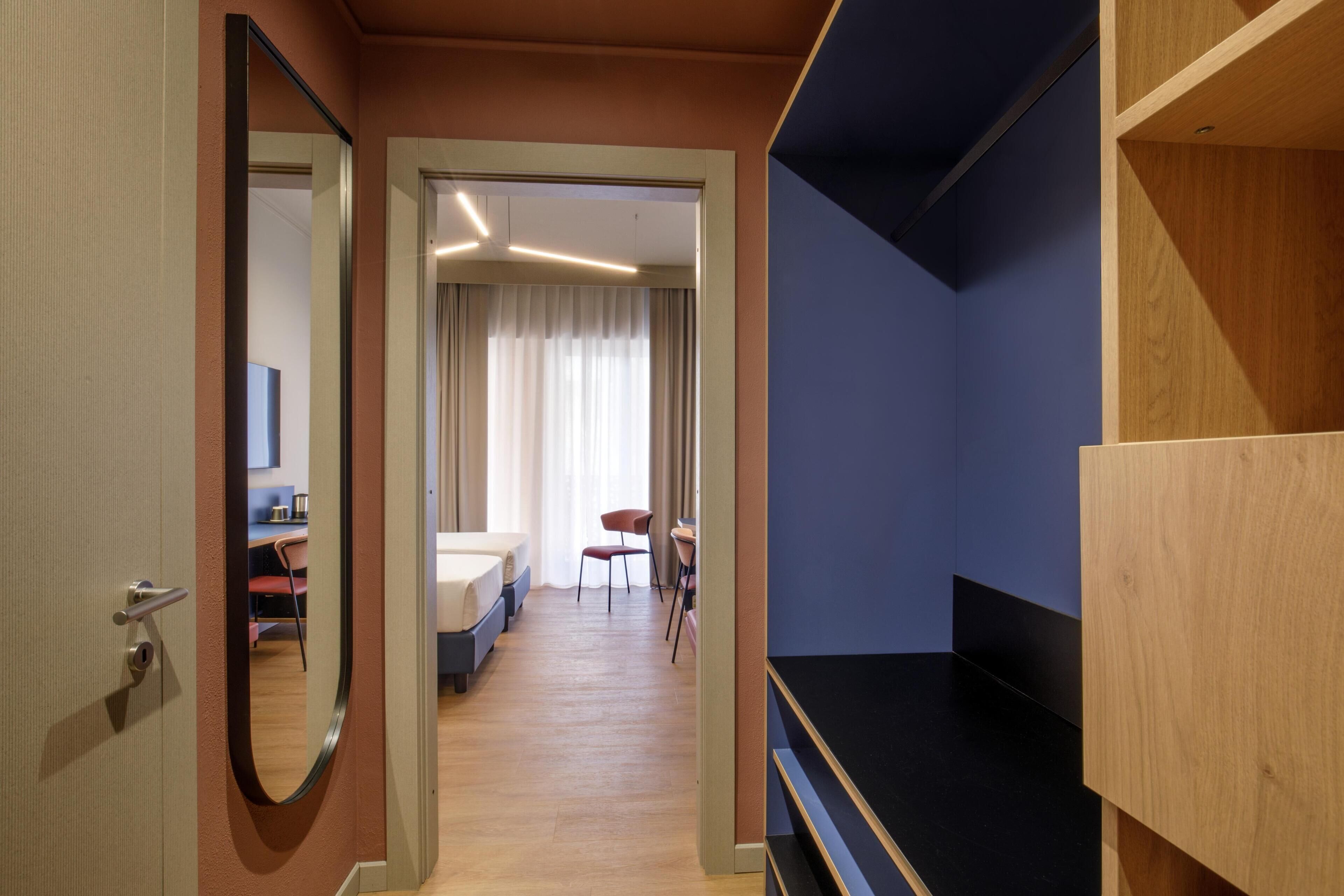 Una camera d'albergo con un letto, una scrivania, una sedia e un armadio.