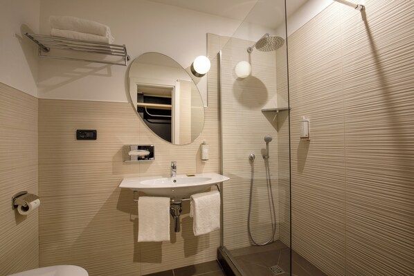 A modern bathroom with a sink, mirror, towel rack, and shower.