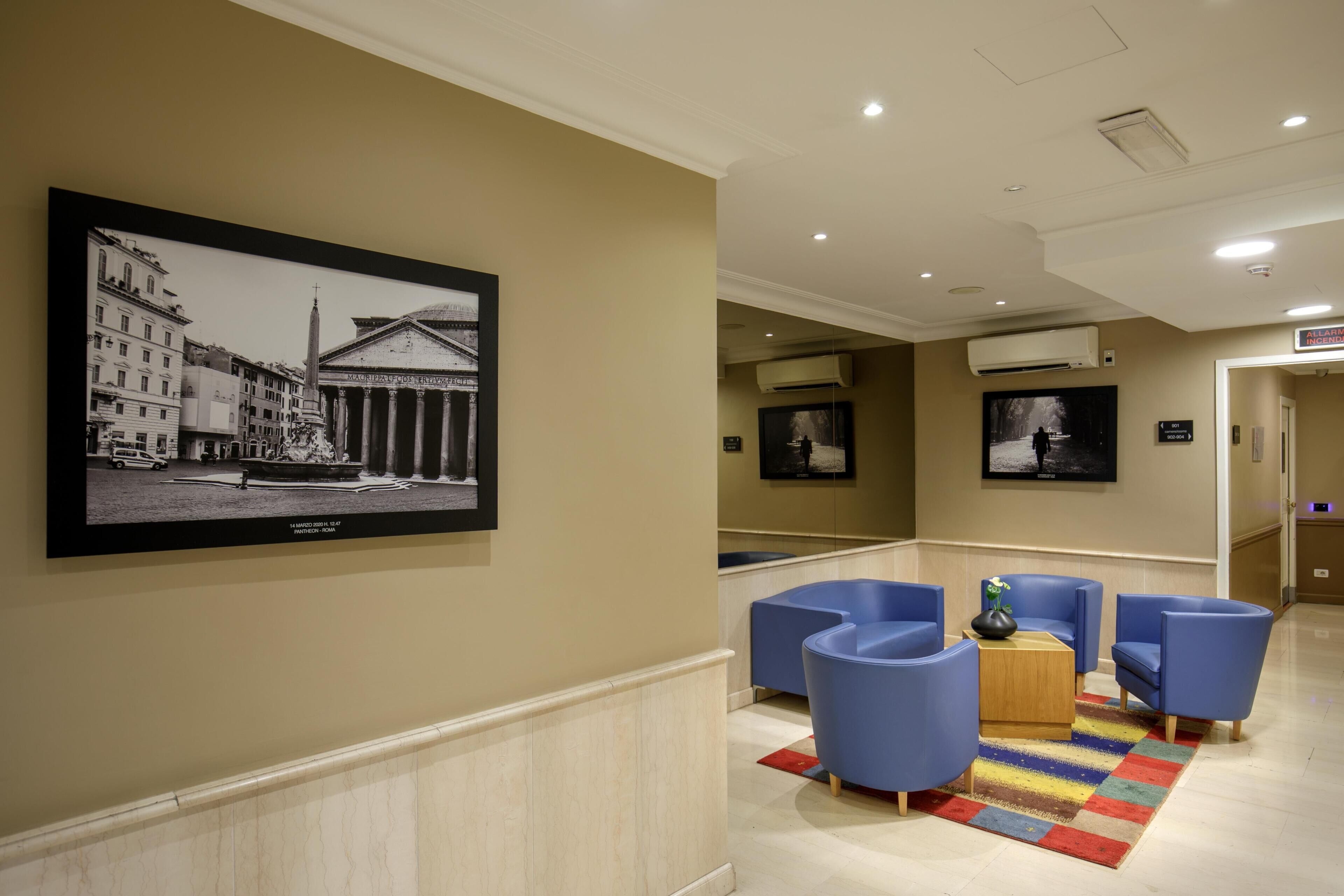 A lobby with a framed black and white photo, blue seating, a colorful rug, and a wooden coffee table.