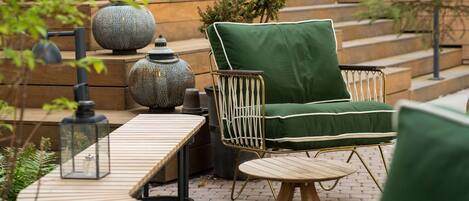 A patio area with a green cushioned chair, a small round table, and a lantern.