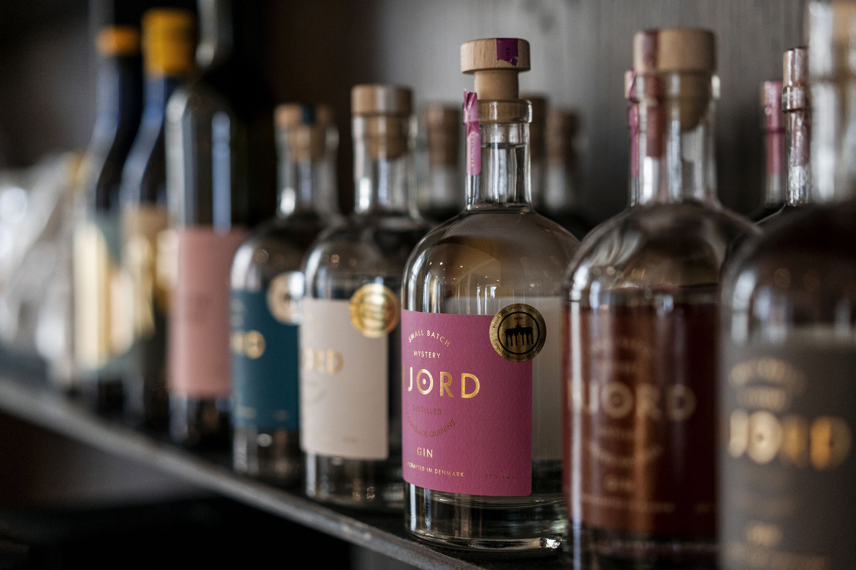 A row of bottles with labels, including one labeled "JORD" and another "MYSTERY".