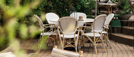 An outdoor patio with wicker furniture and a brick floor.
