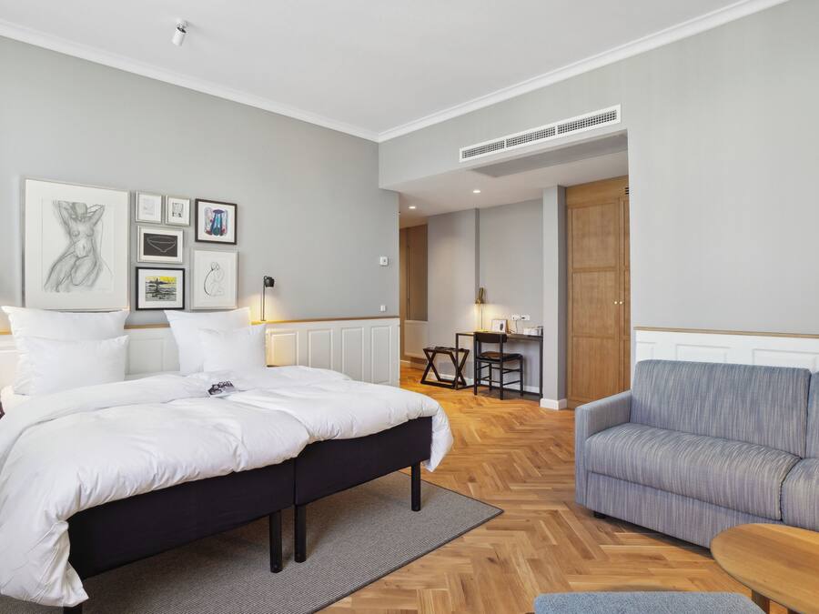 Un dormitorio moderno con una cama grande, un sofá y una zona de comedor.