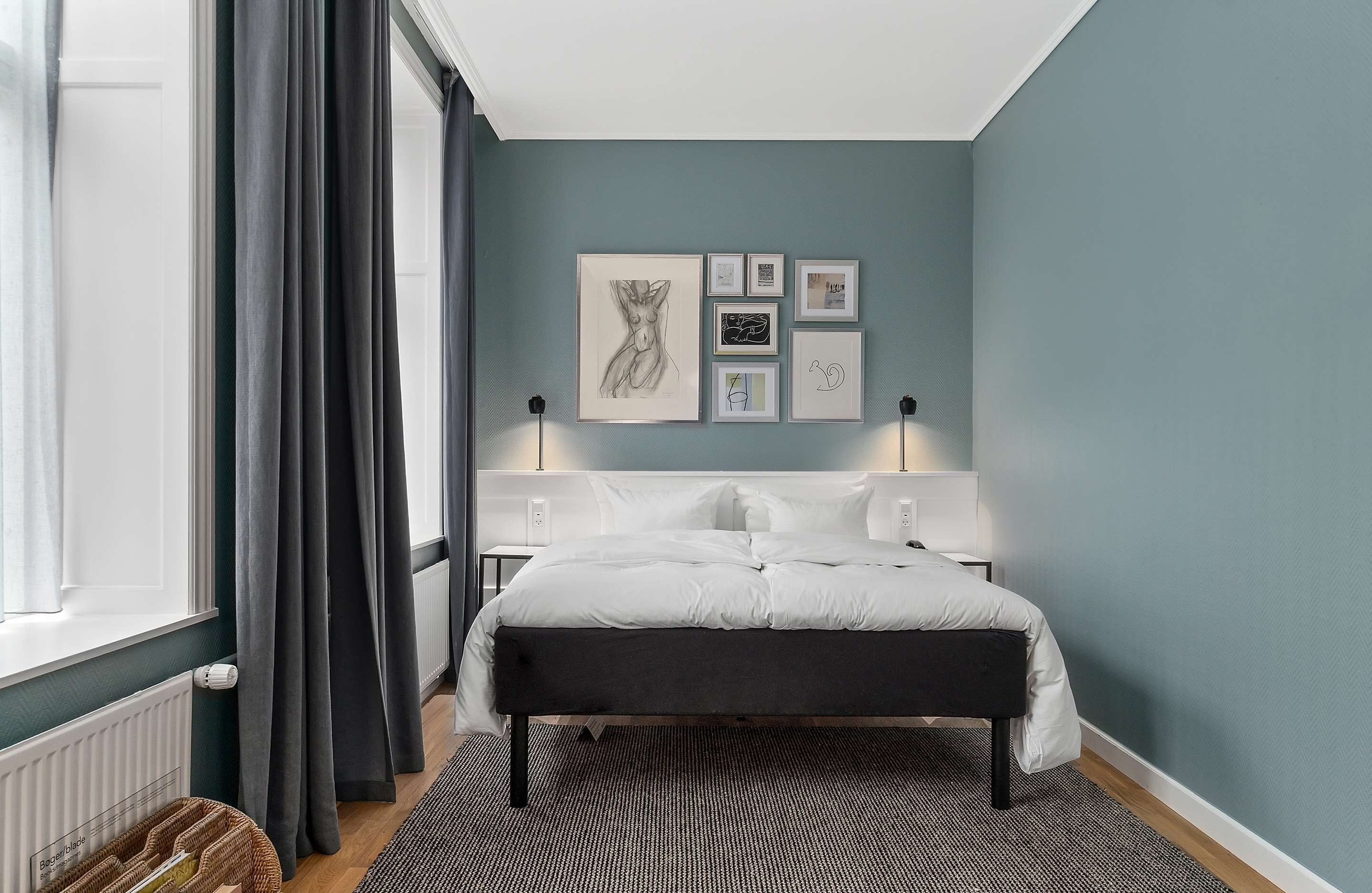 Een moderne slaapkamer met een bed, een hoofdbord en een wand met ingelijste kunstwerken.