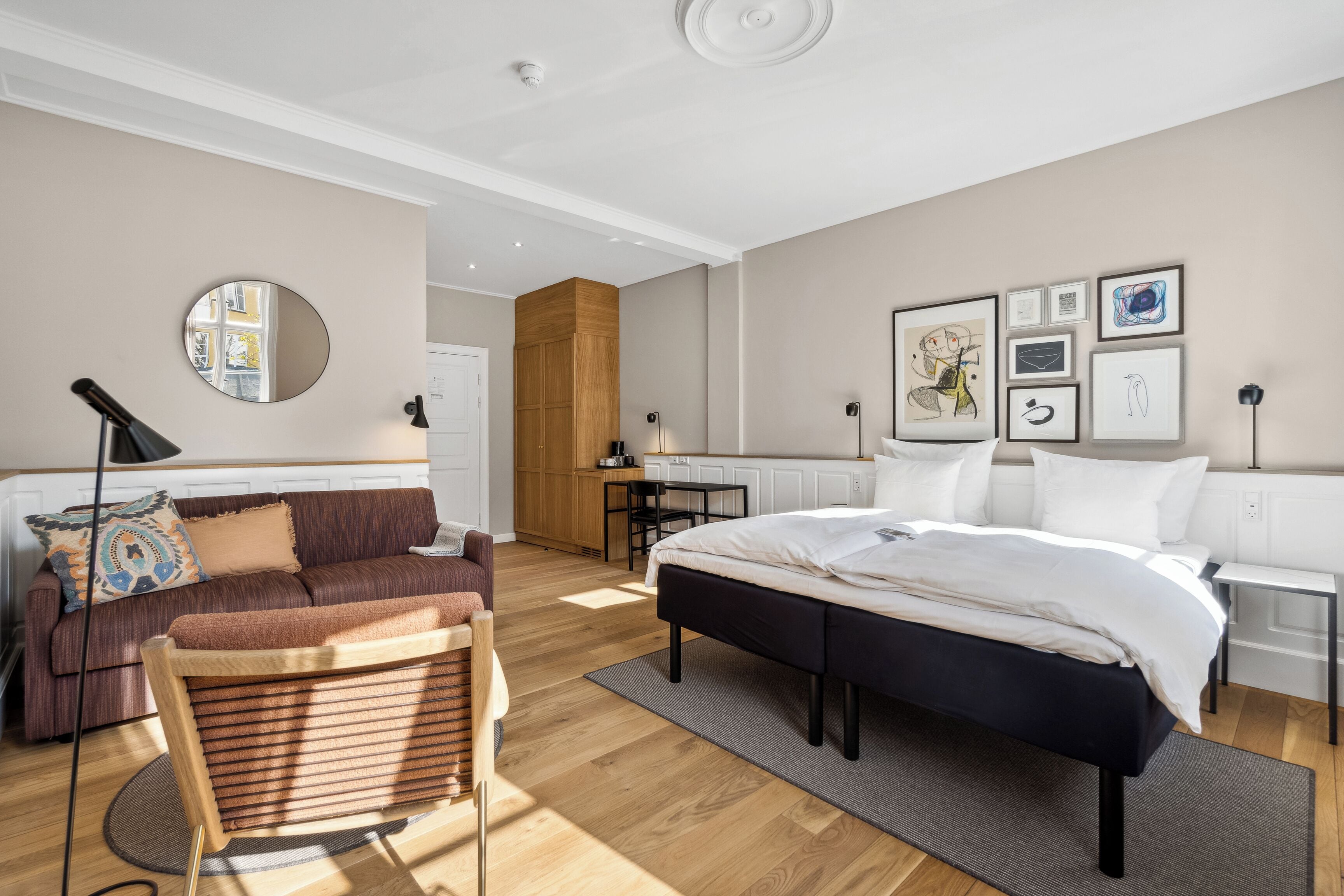 A modern bedroom with a bed, a sofa, a chair, and a desk.