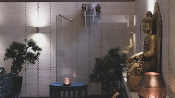 A serene indoor space with a large Buddha statue, a glass partition, and potted plants.