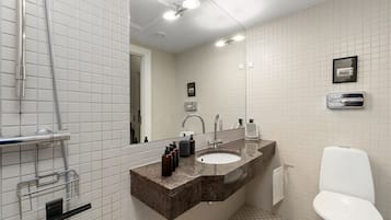 A bathroom with a sink, mirror, toilet, and shower.