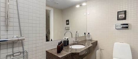 Un baño con lavamanos, espejo, inodoro y ducha.