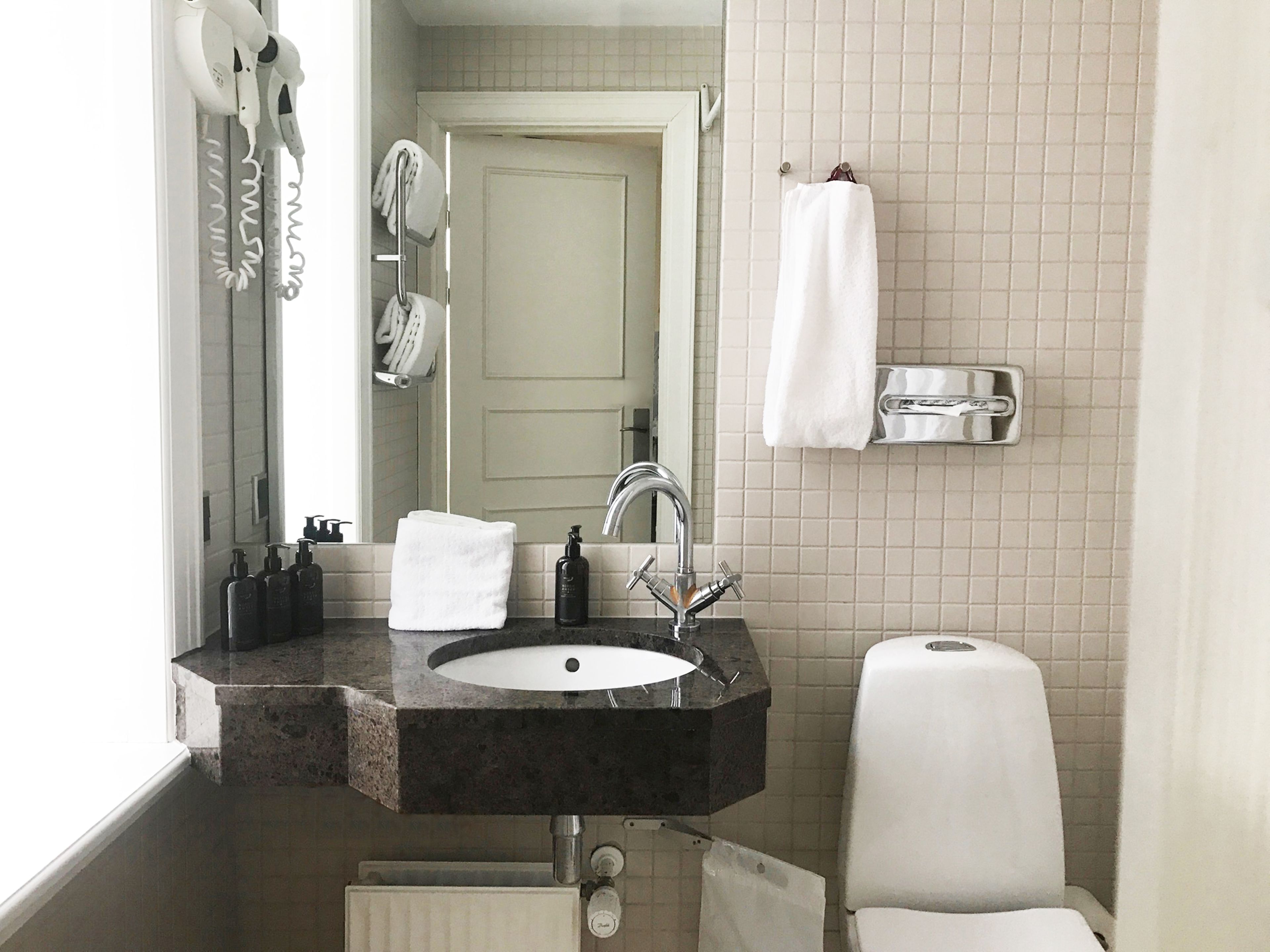 A bathroom with a sink, mirror, towel rack, and toilet.