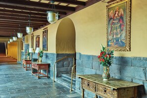 A hallway with stone flooring, wooden benches, and a staircase with a metal railing.