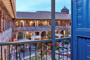 A courtyard with stone arches, outdoor seating, and a view of a historic building with a dome.