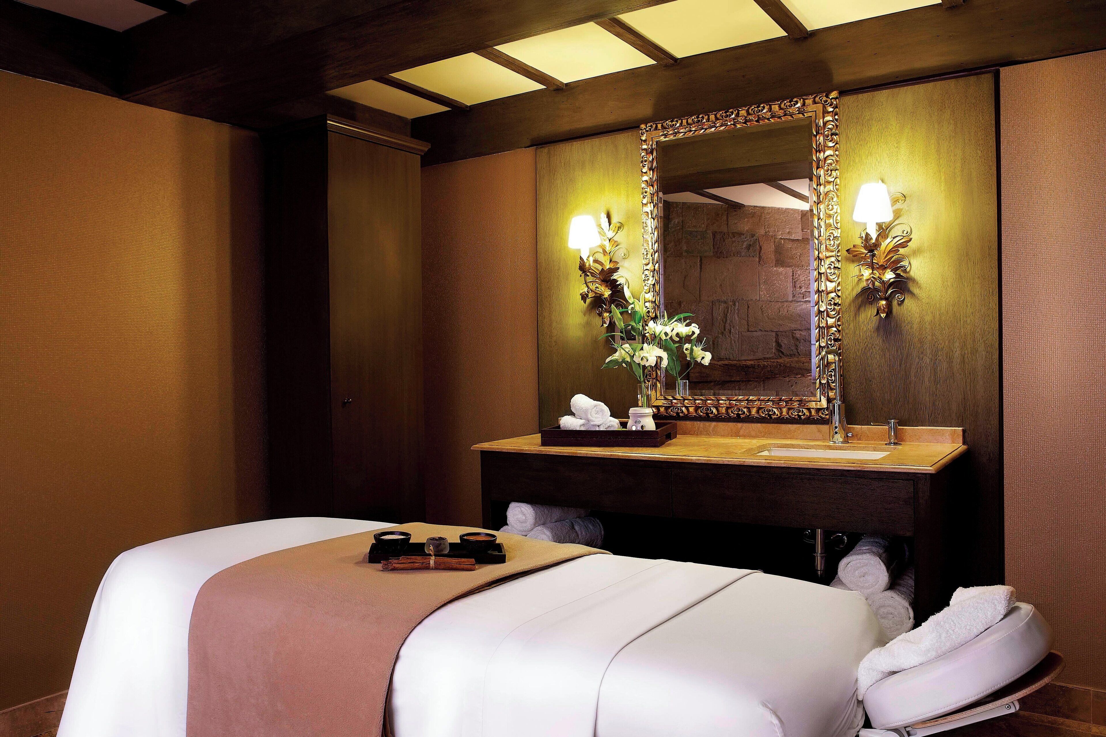 Ein Hotelzimmer mit einem großen Bett, einem Holznähtisch mit Spiegel und zwei Wandleuchten.