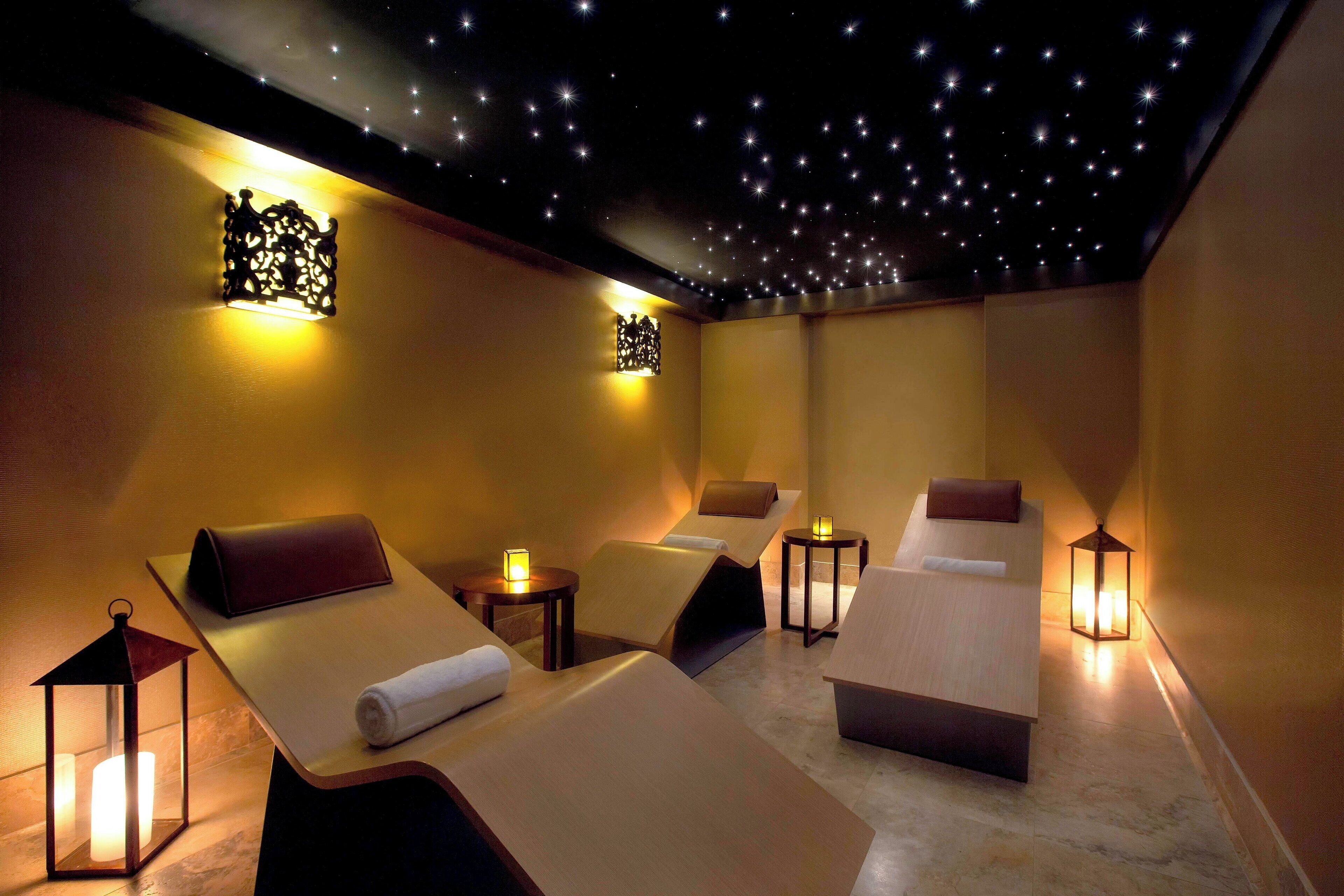A spa room with massage tables, ambient lighting, and a starry ceiling.