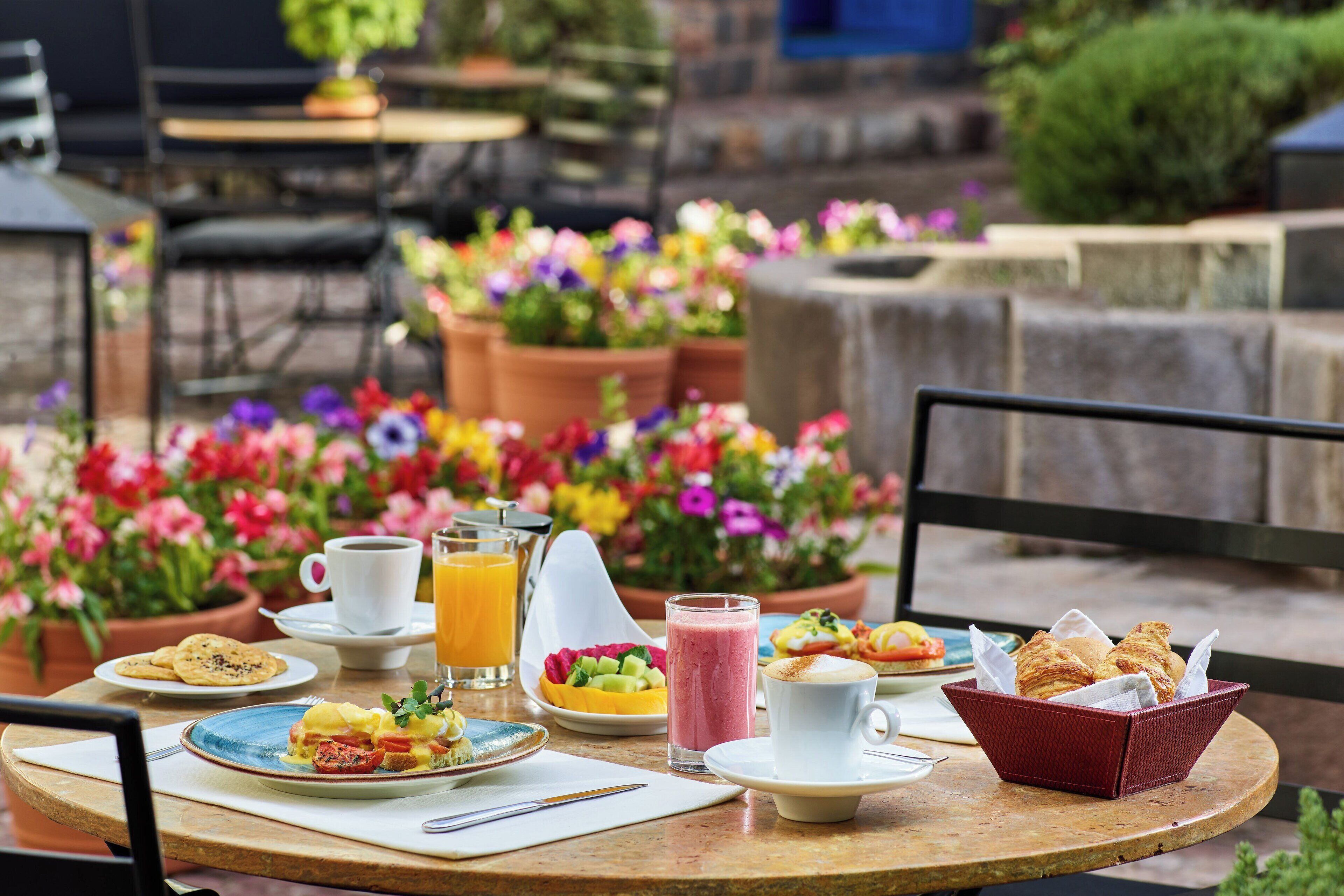 A breakfast table with various dishes, a basket of croissants, and a coffee cup.