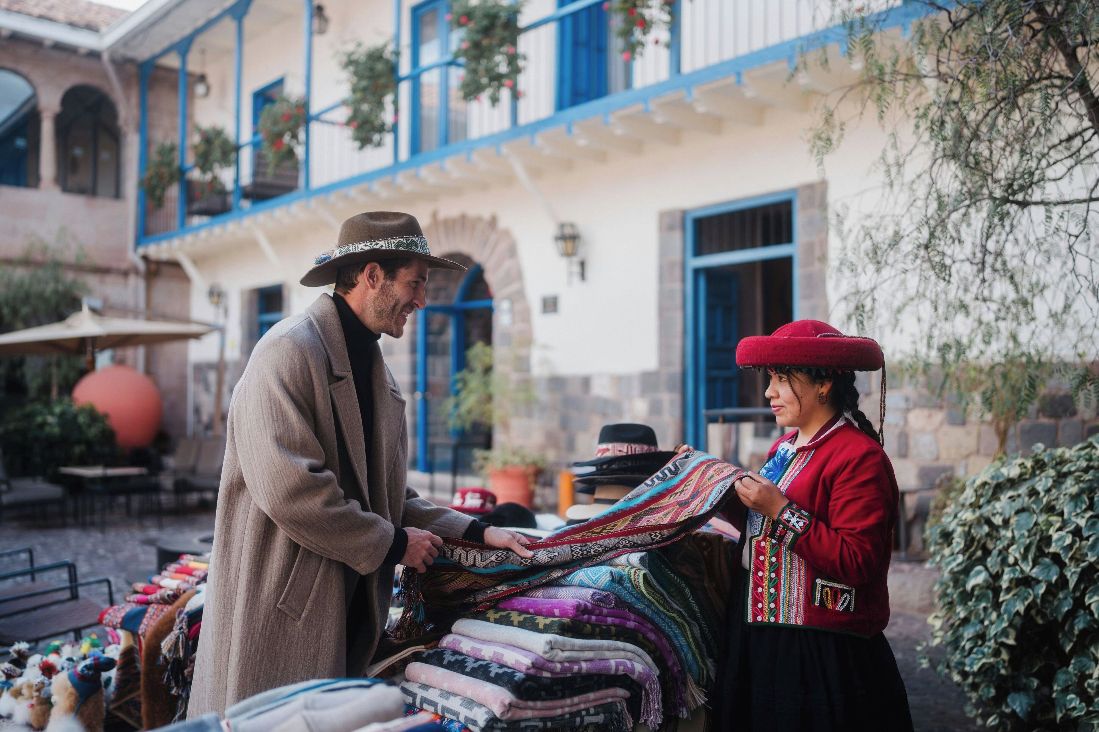 Un home i una dona al davant d'un lloc de venda al mercat, ple de diferents teixits.