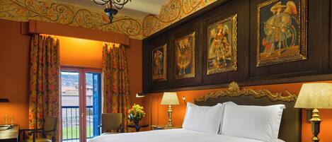 A hotel room with a large bed, two bedside tables with lamps, a chair, a desk, and a view through a glass door.