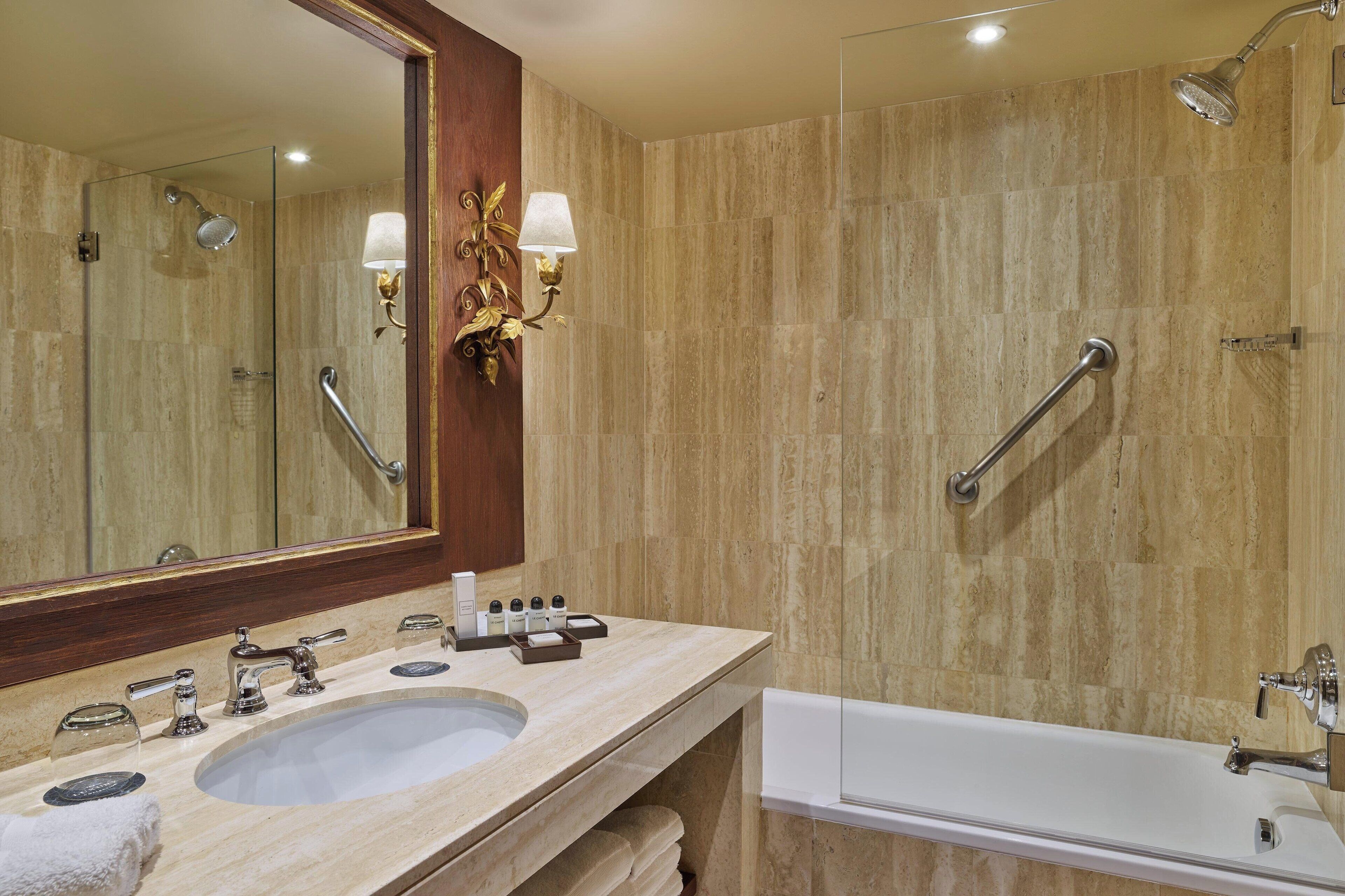 Un baño con lavamanos doble, un espejo grande, ducha con cabezal de ducha manual y bañera.