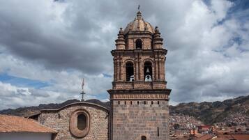 Uma igreja histórica de pedra com uma torre de sino, uma cúpula e uma janela circular.