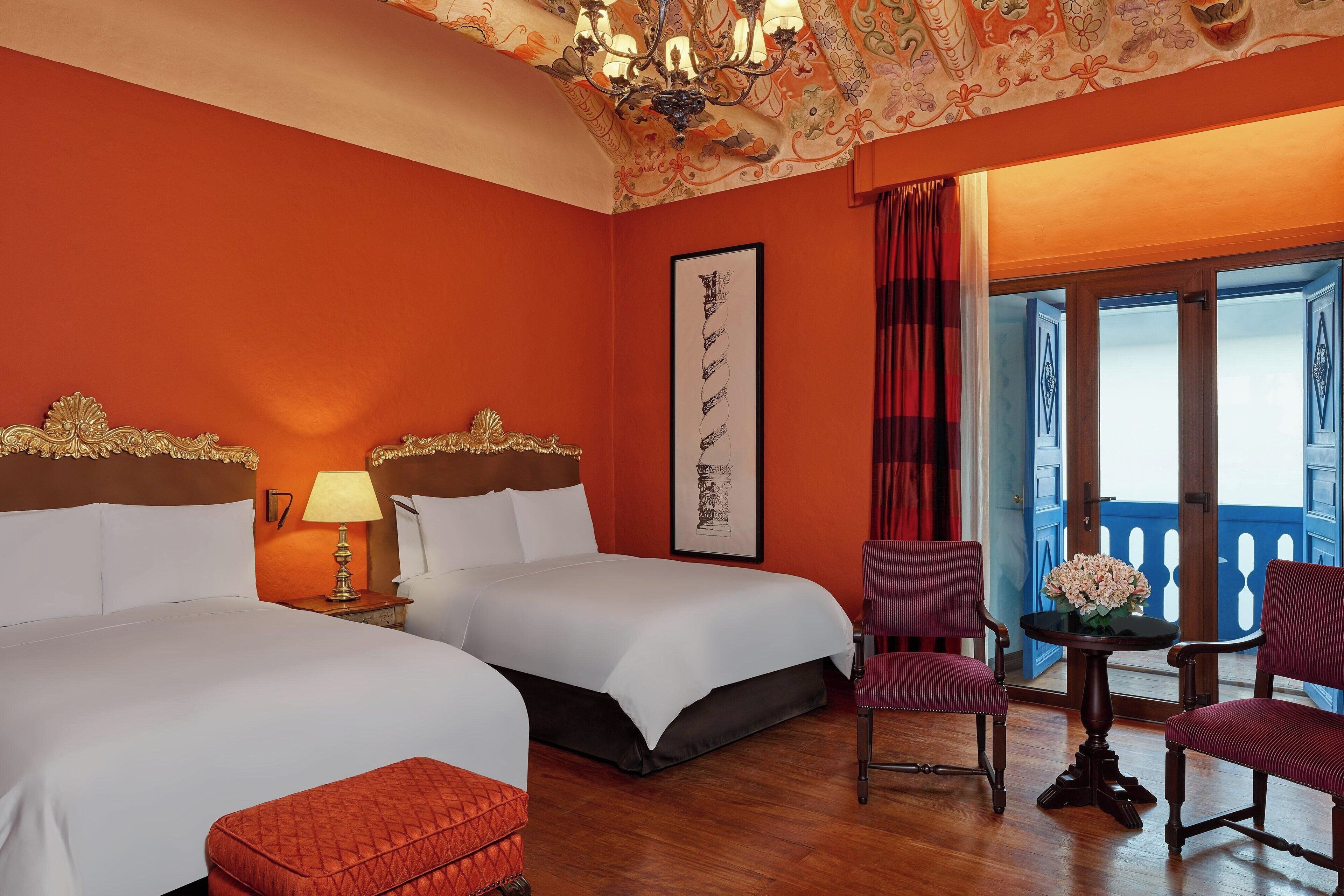 A hotel room with two beds, a table with flowers, and a view of the outside.