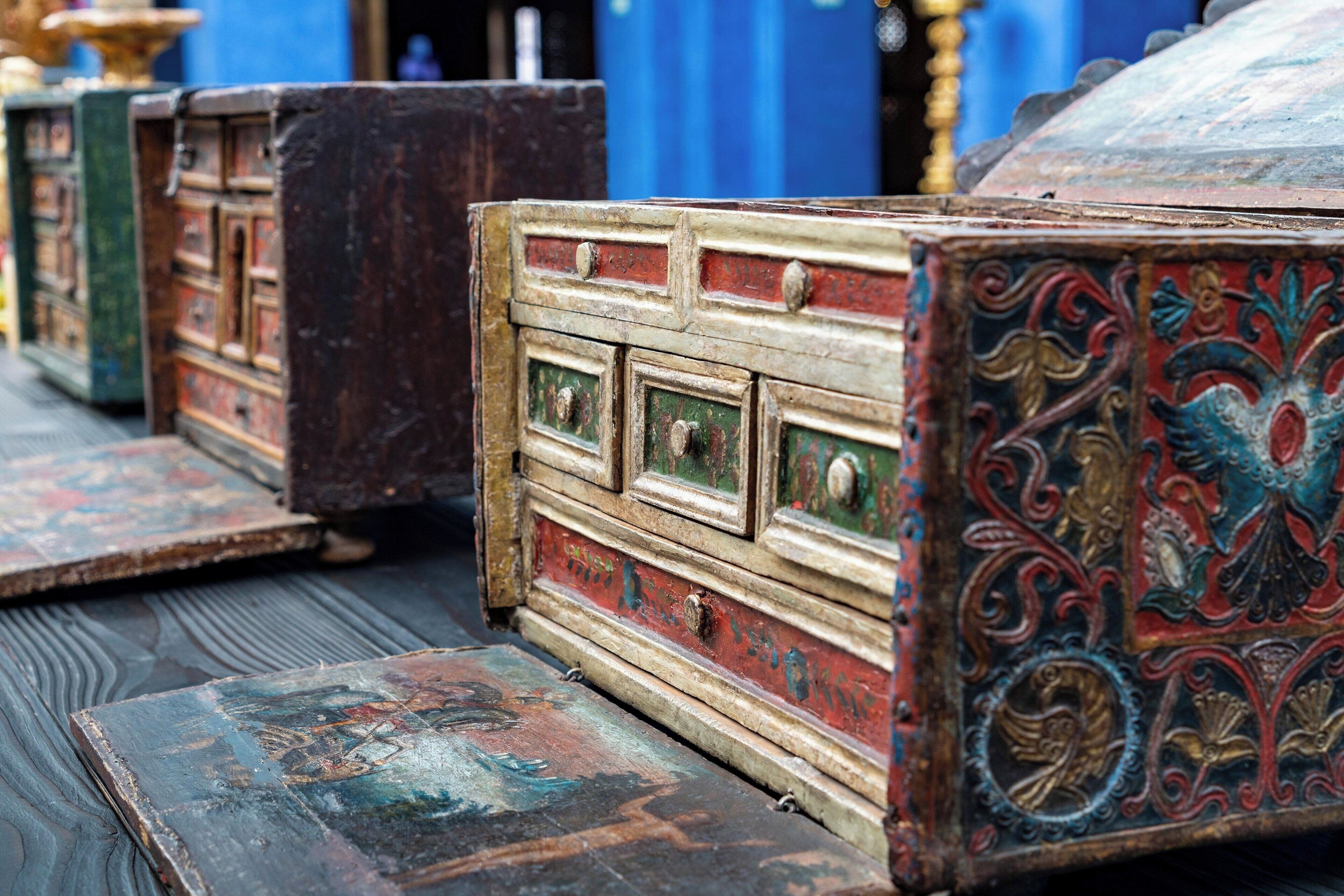 A row of antique wooden chests with intricate carvings, placed on a wooden floor.