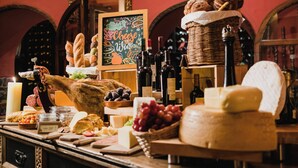 Une dégustation de fromages et de vins, avec une sélection de fromages variés, des raisins, du pain et des bouteilles de vin.