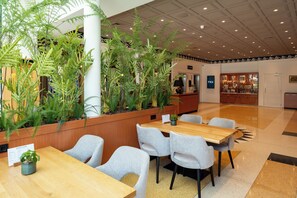 A hotel lobby with a reception desk, seating area, and indoor plants. - Hotel Theater Figi (Zeist)